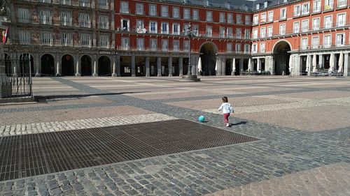 Niña jugando sola con una pelota en la vacía Plaza Mayor de Madrid